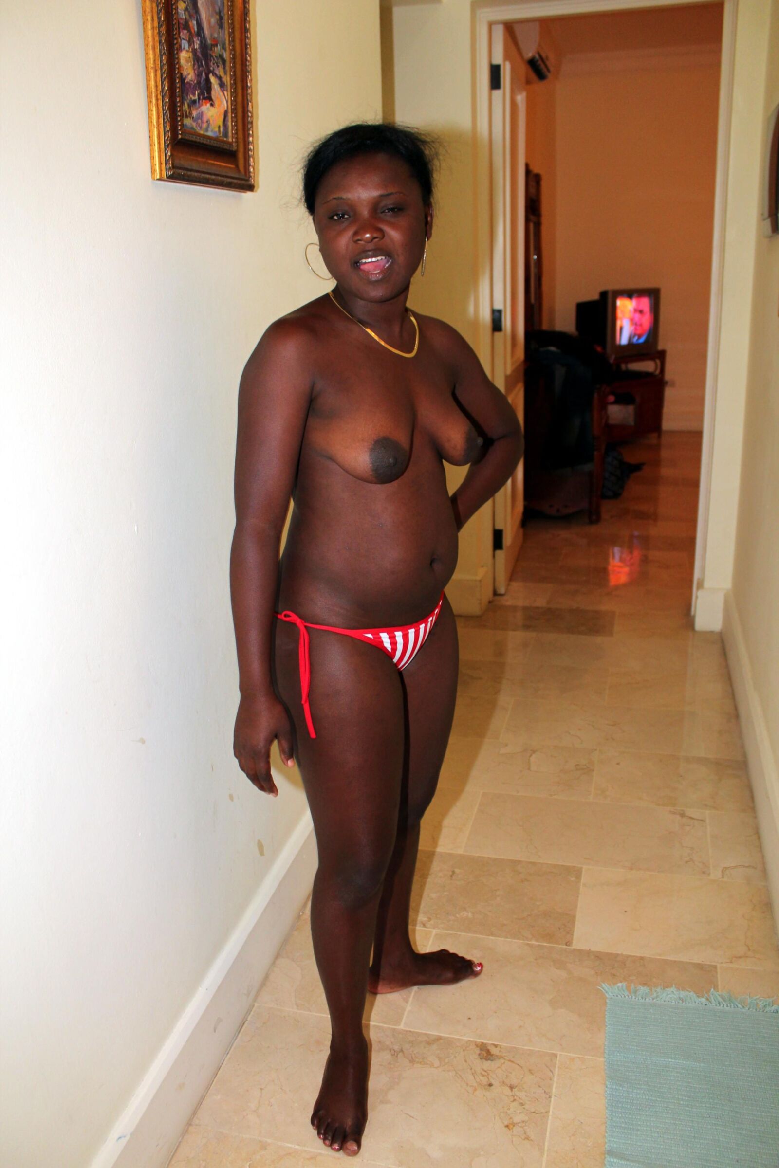Netter schwarzer haariger Haitianer zieht ihren Bikini -Boden an