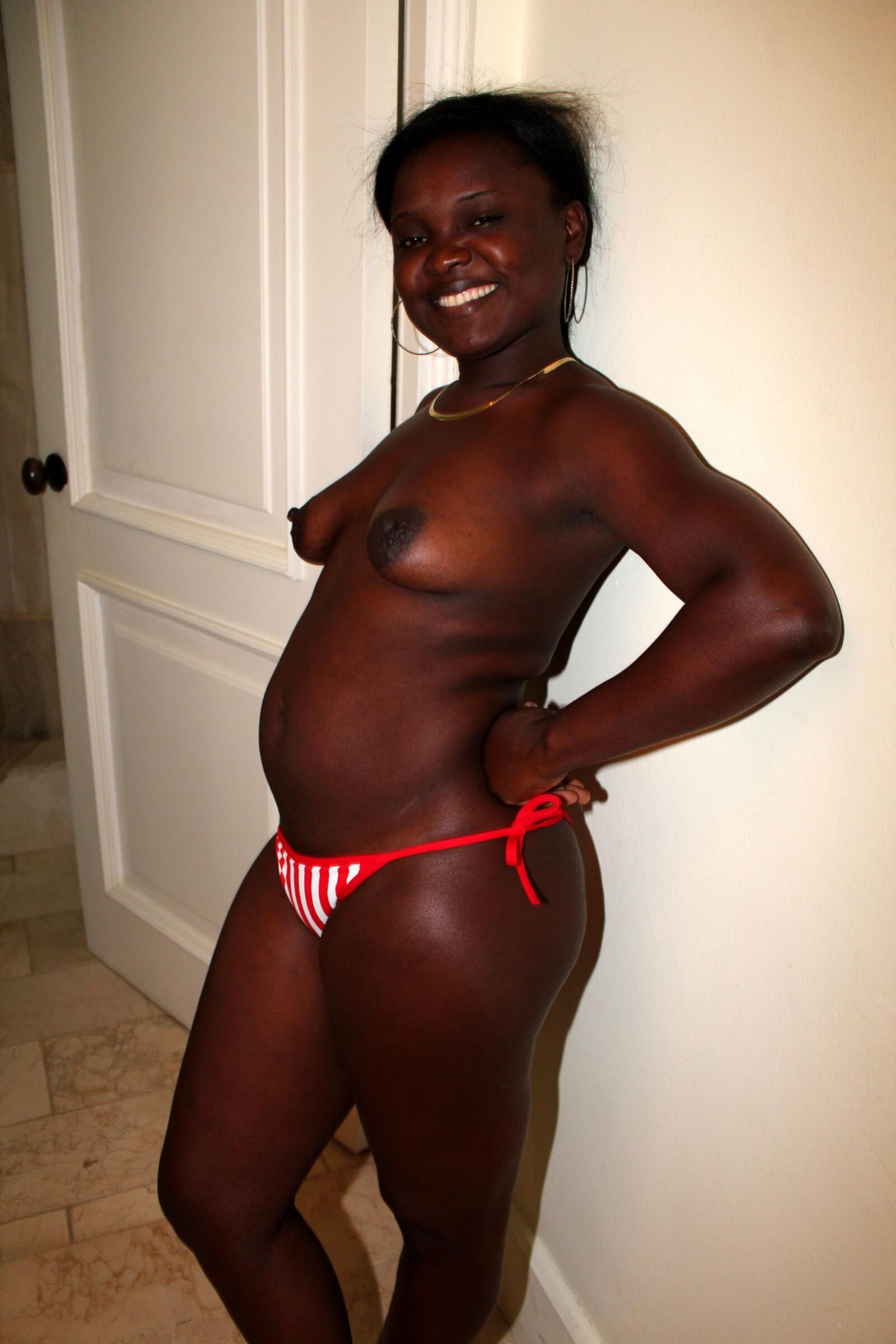Netter schwarzer haariger Haitianer zieht ihren Bikini -Boden an
